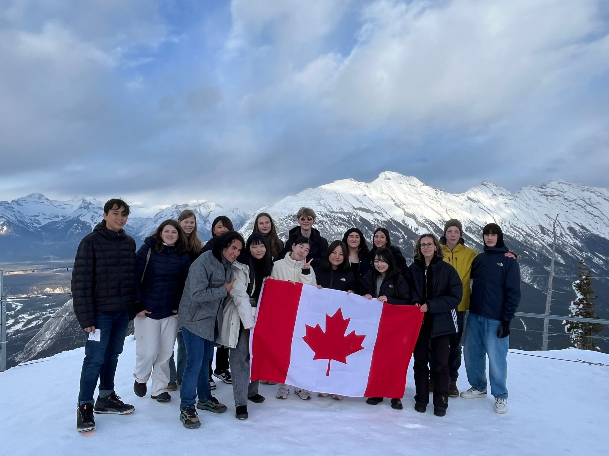 Studenti in Canada con la bandiera canadese durante un’escursione tra montagne innevate.